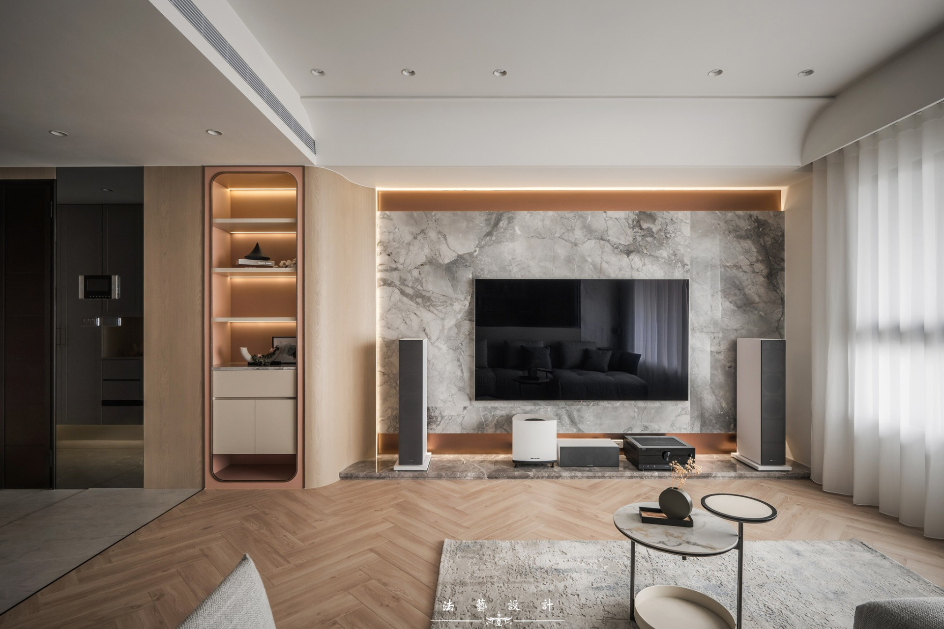 電視牆採用灰階的大理石紋薄磚，與屋主的音響五件組完美呼應，營造沉穩的氛圍之外，也打造男屋主夢想的沉浸式電影院，展示櫃運用弧形木作柔化線條，改善原始屋況的前後差。 